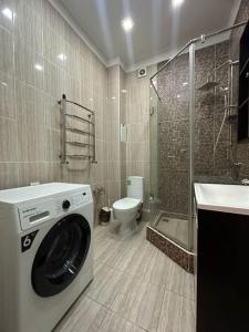 uma casa de banho com uma máquina de lavar roupa e um WC em Студия возле теннисного центра em Aqtöbe