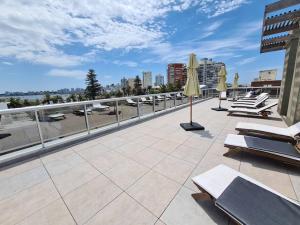 a patio with lounge chairs and umbrellas on a roof at Encantador Apartamento en la mejor ubicación in Punta del Este