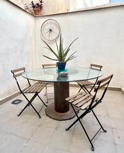 a glass table with two chairs and a plant on a stump at Apartamento San Juan 1 in Murcia