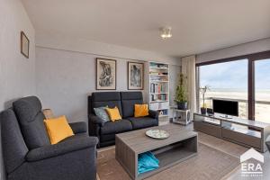 Una sala de estar con un sofá y un televisor en Yquem 0601, en Oostduinkerke