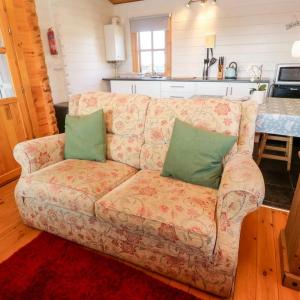 a couch with two green pillows on it in a kitchen at Trevenna Cabin in St Austell