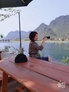 een vrouw op een bankje die een foto van een meer neemt bij Riverview Home in Quang Binh