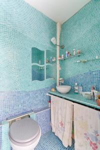 een blauw betegelde badkamer met een toilet en een wastafel bij Résidor - Cozy studio 10 minutes from Paris in Les Lilas