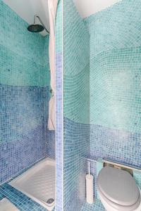 een blauwe betegelde badkamer met een toilet en een douche bij Résidor - Cozy studio 10 minutes from Paris in Les Lilas