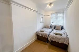 2 camas en una habitación pequeña con ventana en Stunning house, sleeps 10, garden and pool table - West Parley Manor, en West Parley