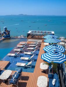 eine Reihe blauer und weißer Sonnenschirme und der Ozean in der Unterkunft Siam@Siam Design Hotel Pattaya in Pattaya