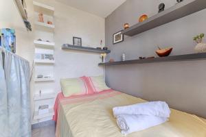 een kleine slaapkamer met een bed en planken bij Résidor - Cozy studio 10 minutes from Paris in Les Lilas