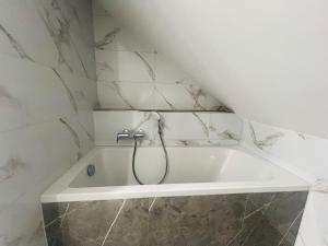 La salle de bains est pourvue d'une baignoire blanche et d'une douche. dans l'établissement Apartment Weikersheim II, à Weikersheim