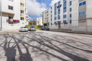 a shadow of a building on a street with parked cars at Agualva Happy Apartment in Paiõis