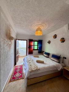 Un dormitorio con una cama grande y una lámpara de araña. en Natural Surf House en Tamraght Ouzdar