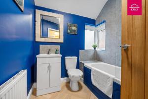 ein blaues Badezimmer mit Toilette und Badewanne in der Unterkunft Accessible ground floor wet room and bedroom in a modern 4 Bedroom House-B28 Hall Green in Birmingham