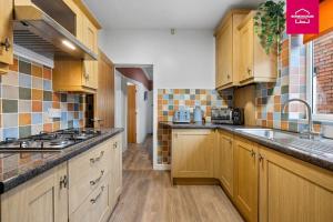 eine große Küche mit Holzschränken und einem Waschbecken in der Unterkunft Accessible ground floor wet room and bedroom in a modern 4 Bedroom House-B28 Hall Green in Birmingham + 22 Fotos