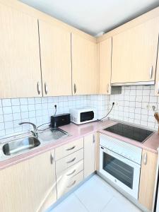 a kitchen with wooden cabinets and a sink and a microwave at Apartamento San Juan 1 in Murcia