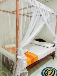 a bedroom with a bed with a mosquito net at Tashil Hotel & Restaurant in Tissamaharama