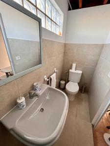 ein Badezimmer mit einem Waschbecken, einem WC und einem Spiegel in der Unterkunft Integral surf yoga in El Médano