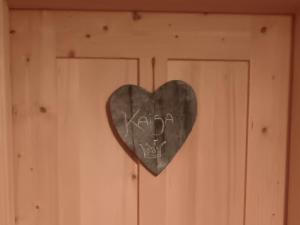 ein Herz hängt an einer Holztür mit Graffiti in der Unterkunft Kofelhof in Sexten