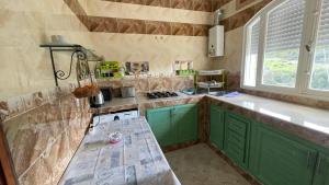 cocina con armarios verdes, fregadero y ventana en Traditional forest villa, 