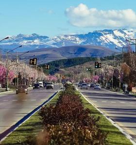 a street with traffic lights and snow covered mountains at El cahuquen casa 2 dormitorios in Junín de los Andes
