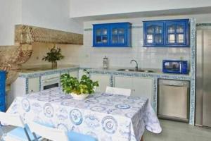 een keuken met een tafel en blauwe kasten bij Espectácular piso en casa sXVIII frente a Salomé in Santiago de Compostela
