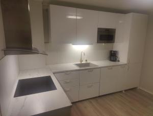 a kitchen with white cabinets and a sink and a stove at Vardø accommodation - white house in Vardø