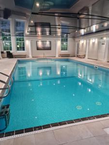 a large swimming pool with blue water in a building at Wyndham Trenython Manor in Fowey