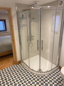 a glass shower in a bathroom with a checkered floor at The Cartlodge in Debenham