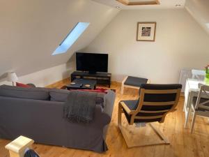 ein Wohnzimmer mit einem Sofa und einem TV in der Unterkunft The Cartlodge, Debenham in Debenham