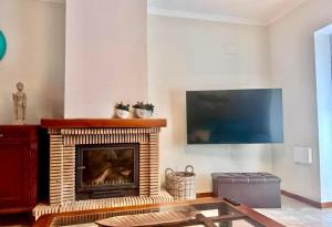 sala de estar con chimenea y TV de pantalla plana en Chalet en la Barrosa, en Novo Sancti Petri