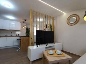 ein Wohnzimmer mit einem TV und einem Tisch sowie eine Küche in der Unterkunft Apartamento RyR in Padrón