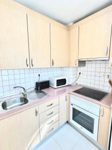 Kuchnia z drewnianymi szafkami, zlewem i kuchenką mikrofalową w obiekcie Apartamento San Juan 2 w Murcji