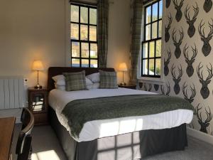 a bedroom with a large bed with two windows at Cuil-An-Daraich Guest House in Pitlochry