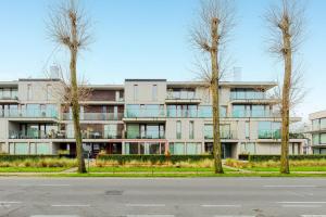 an apartment building with trees in front of a street at Maremonte Gv02 in Oostduinkerke