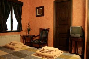 a bedroom with a bed and a tv and a chair at La Posada del Hidalgo de Alarcón in Alarcón