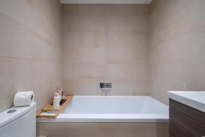 Niru Experience-Earl's Court Charm 2BD 2 BA في لندن: حوض استحمام أبيض في حمام مع حوض