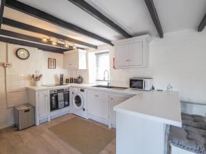 a kitchen with white cabinets and a washer and dryer at The Coach House Newcastle Emlyn in Newcastle Emlyn +8 photos