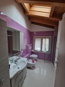 bagno con pareti viola, lavandino e servizi igienici di LA CASA DI ALICE a Lenno