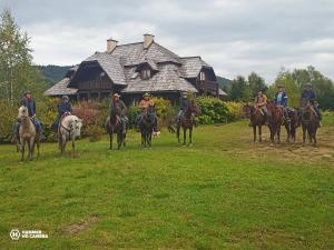 齊斯的住宿－Sosnowy Dwór，一群人骑马在房子前