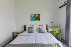 a bedroom with a bed and a green chair at Casa Yumi in Denpasar