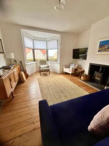 a living room with a blue couch and a fireplace at Sealladh Na Mara, Pittenweem in Pittenweem