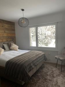 een slaapkamer met een bed en een groot raam bij Appartement à deux pas du centre de Crans-Montana in Crans-Montana