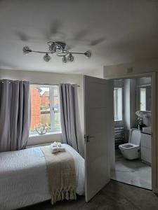 a bedroom with a bed and a window and a toilet at The JN Grove in Peterborough