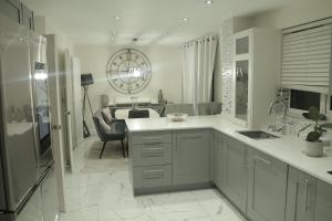 a kitchen with white cabinets and a living room at The JN Grove in Peterborough