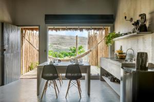 cocina con mesa, 2 sillas y ventana en Vila Flor Studios, en Praia de Moitas
