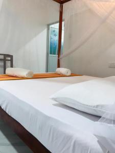 a white bed with two towels on top of it at Tashil Hotel & Restaurant in Tissamaharama