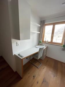 Cette chambre dispose d'une fenêtre et d'un bureau blanc avec une chaise. dans l'établissement Ferienwohnung BodnLois, à Matrei in Osttirol