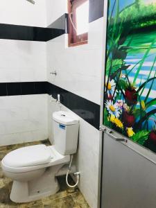 a bathroom with a toilet and a painting on the wall at Tashil Hotel & Restaurant in Tissamaharama
