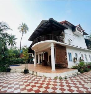 a large white house with a balcony on top of it at Garnet Crove Villa in Alibag