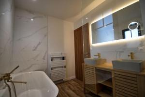 uma casa de banho com 2 lavatórios, uma banheira e um espelho. em Maison Arcachonnaise neuve et grande terrasse em La Teste-de-Buch