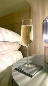 a glass of wine on a table next to a bed at Modern Town House in Cotswolds - 3 double bedrooms in Witney