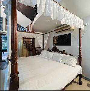 Schlafzimmer mit Himmelbett und weißer Bettwäsche in der Unterkunft Garnet Crove Villa in Alībāg